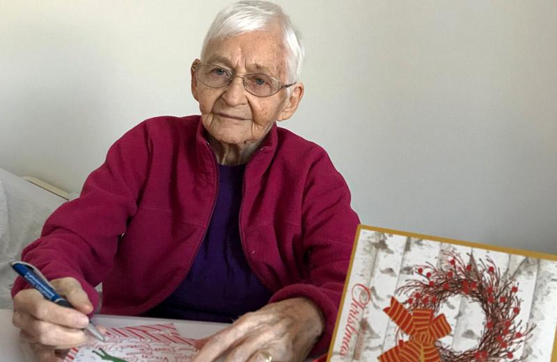An elderly woman writes a Christmas card.