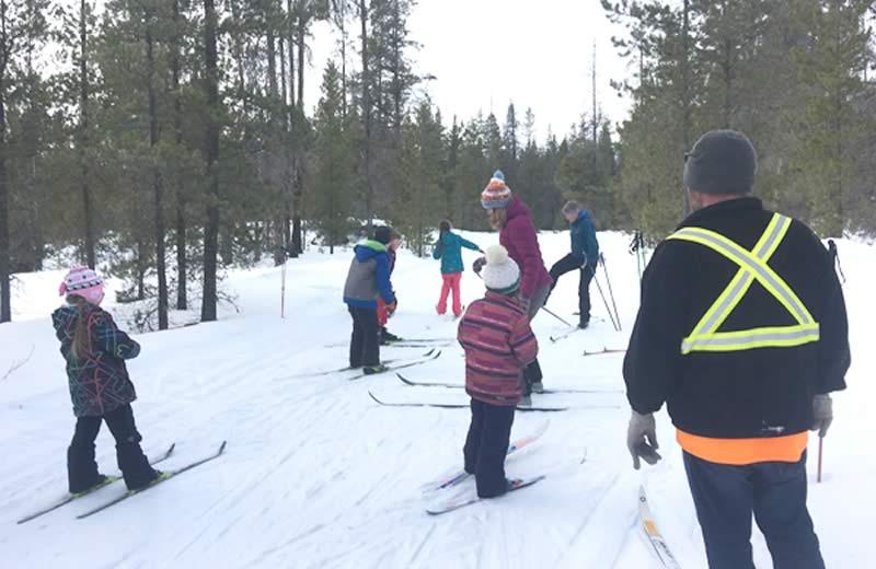 Group of kids, wearing bright jackets and hats, cross country skiing.