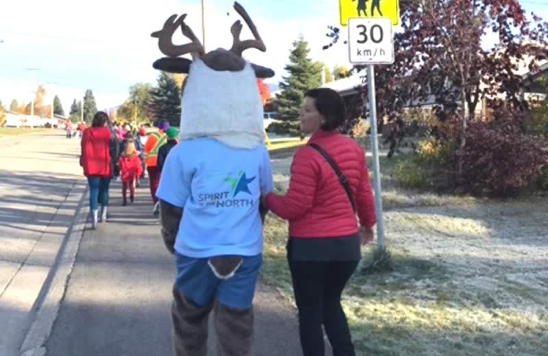 NH Mascot, Spirit the Caribou, walking to school with woman wearing read puffer jacket..