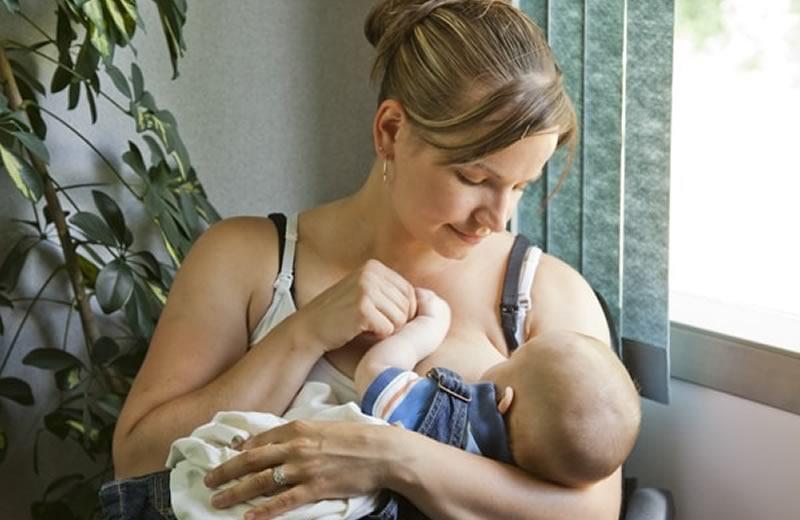 Woman with hair pulled up breastfeeding her baby.