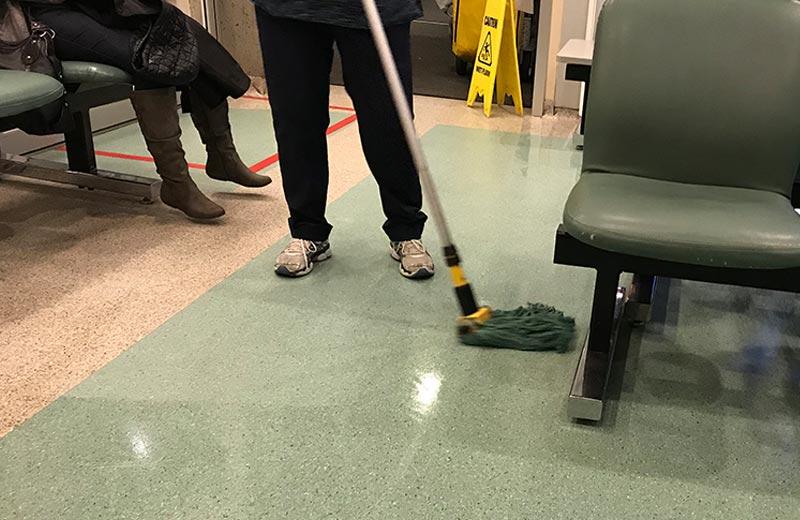 A woman mops the floor of a hospital waiting room.