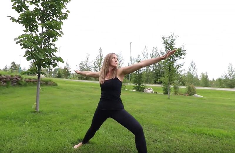 Girl doing a yoga pose on a grassy field.