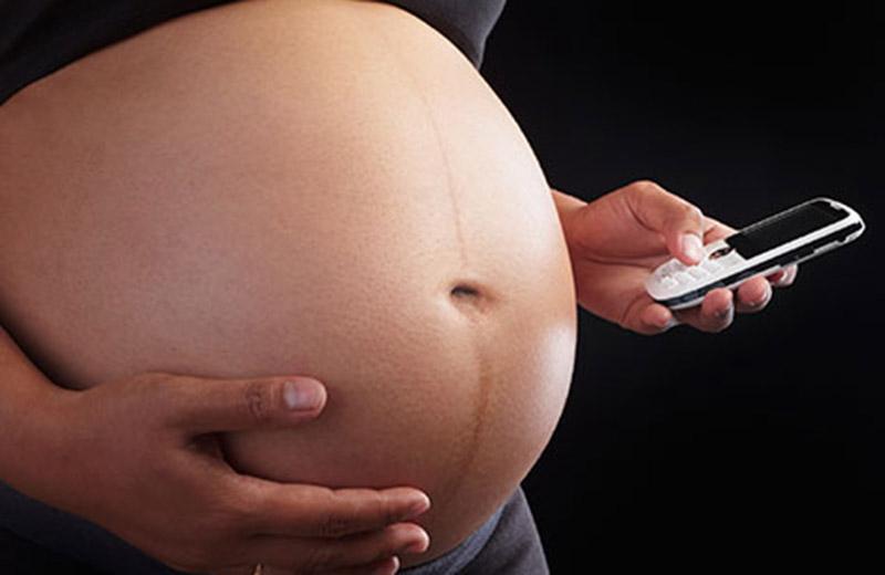 Pregnant person holding a cell phone.