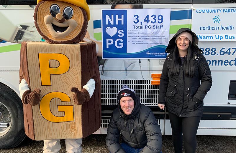 The Mr. PG mascot stands with a crouching man and a standing woman next to the NH Connections bus.