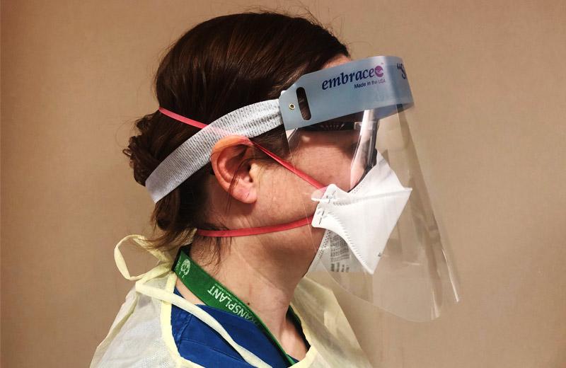 A side view of a nurse wearing a face mask and gown. 