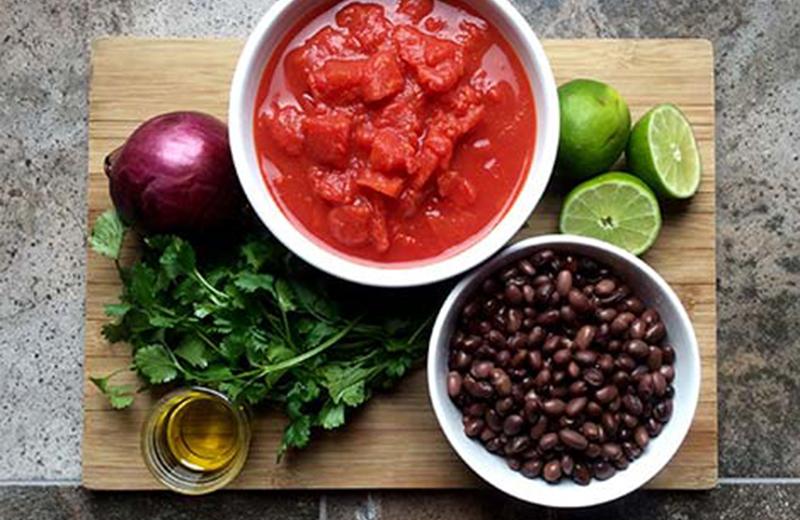 Ingredients to make black bean salsa displayed on a cutting board