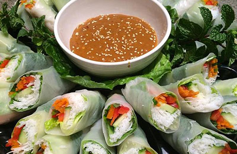 Fresh spring rolls stacked on a plate with dip