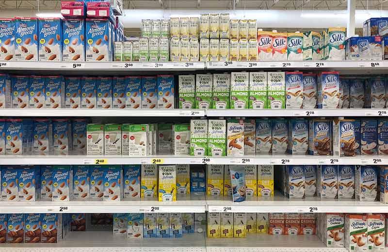 Cartons of plant-based beverages line section of the grocery store.