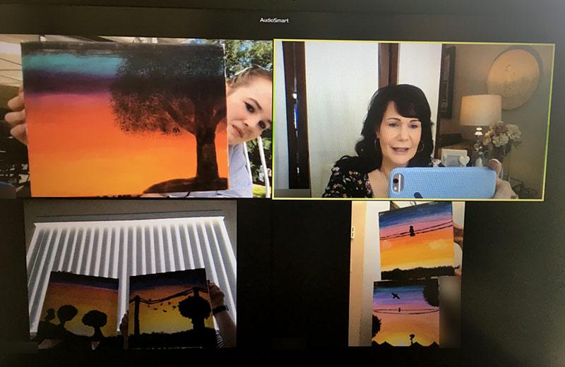 On a video chat, three youth hold up paintings while another person takes a picture.