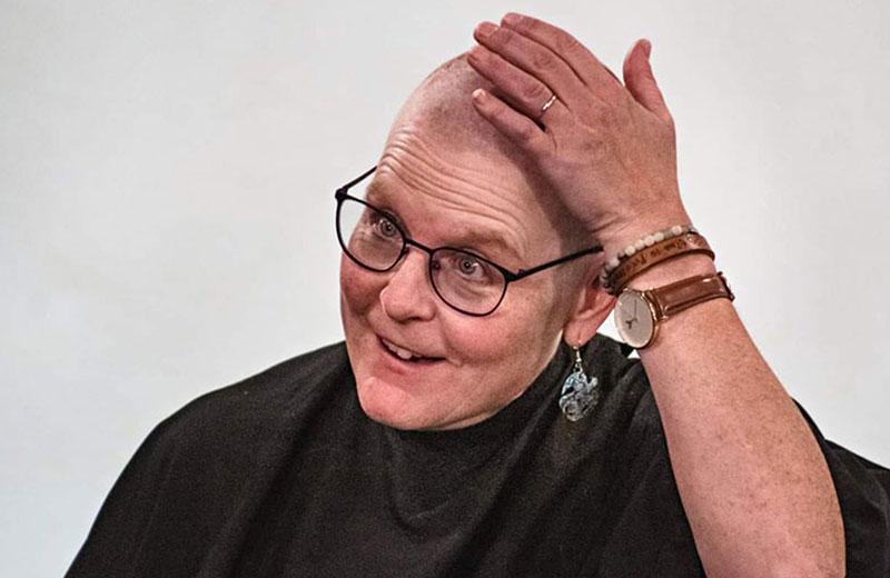 Woman with glasses touches head after having it shaved
