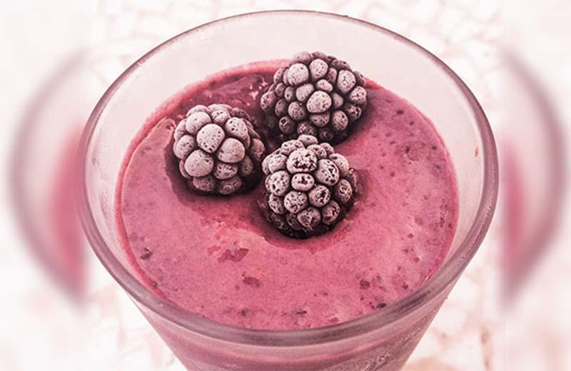 Berry smoothie with three blackberries on top.