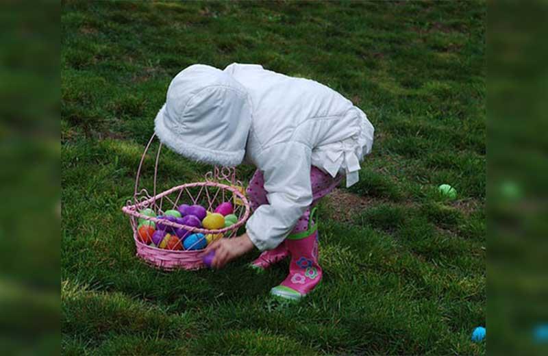 Child picking up coloured Easter eggs.