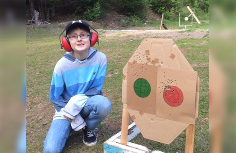 Boy sitting beside a shooting target