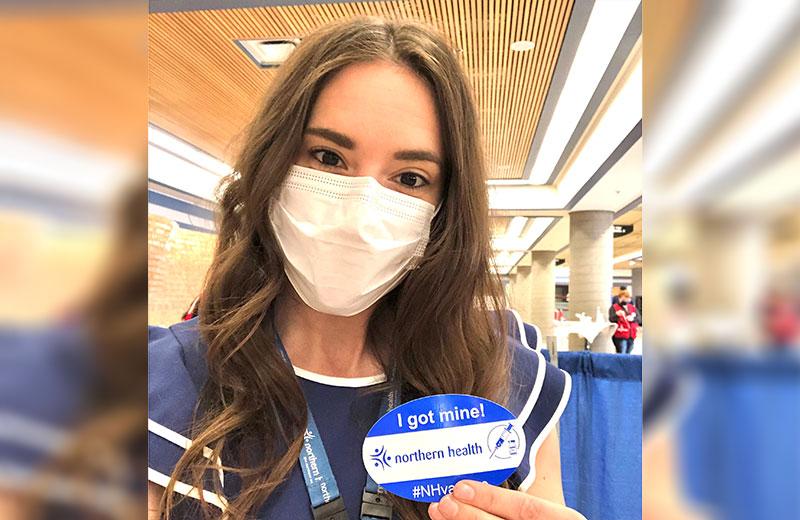 Woman in a mask shows off a get vaccinated sticker
