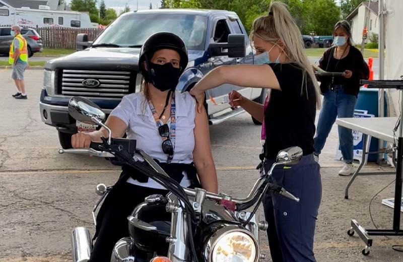 Woman on motorcycle getting her COVID-19 vaccine.