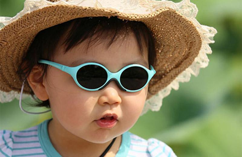 Child outside wearing sun hat and sunglasses