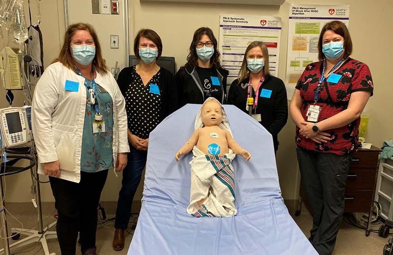 a group of health care professionals pose with the sim baby 