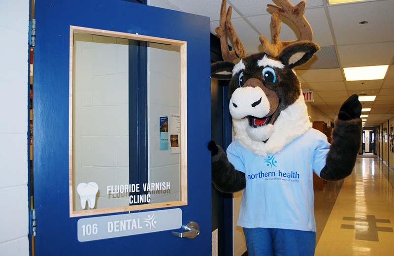 The NH mascot (a giant caribou in a blue shirt) stands next to a dental clinic door