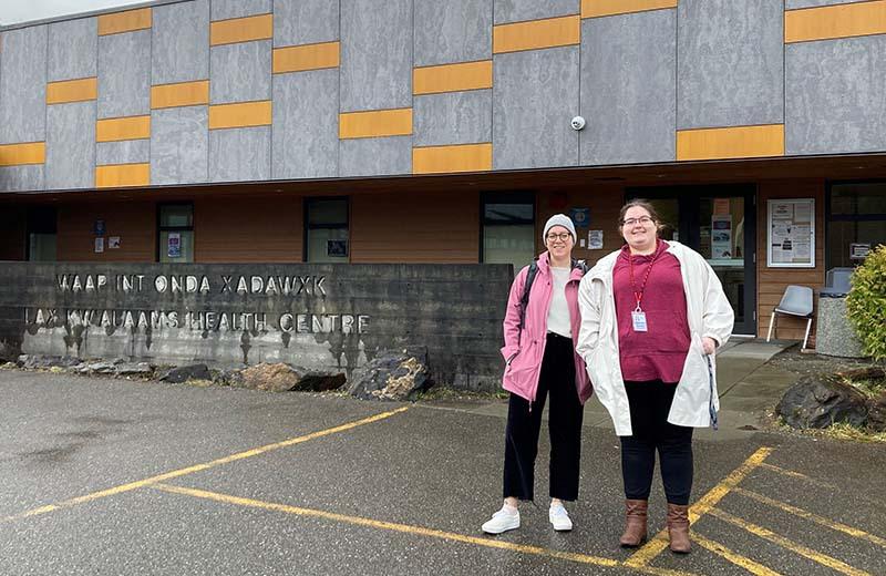 two woman stand outside in front of the health care centre
