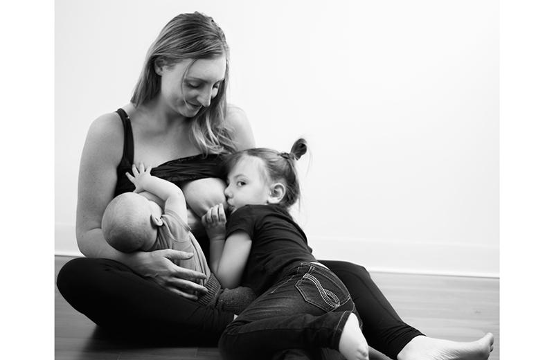 Woman tandem breastfeeding baby and toddler. 
