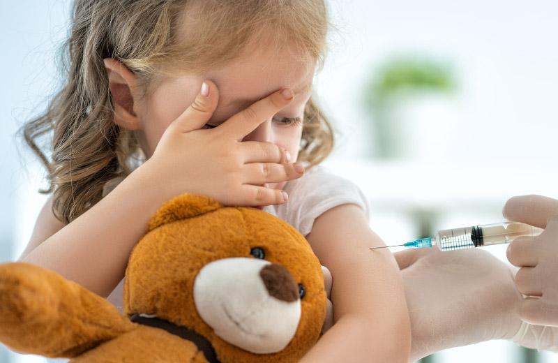 Child covers eyes while getting needle in her arm