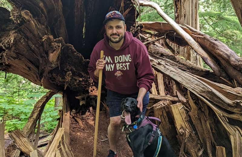 Man hiking with a dog in a heavily treed area