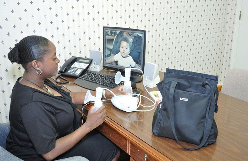 Woman sits at a desk pumping breast milk.