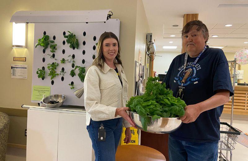 NH staff holding a bowl of resh green picked from NH gardens