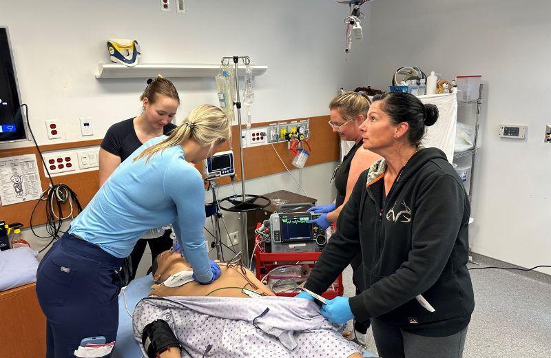 Trainees stand around a dummy on a gurney, while testing the new equipment.