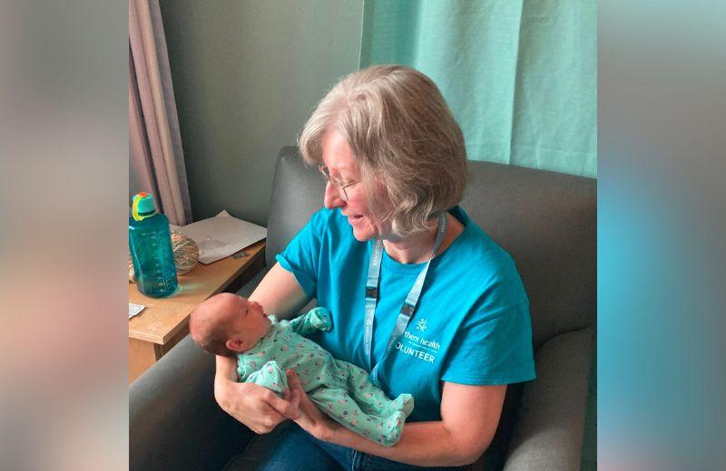 Woman wearing blue shirt holding a baby