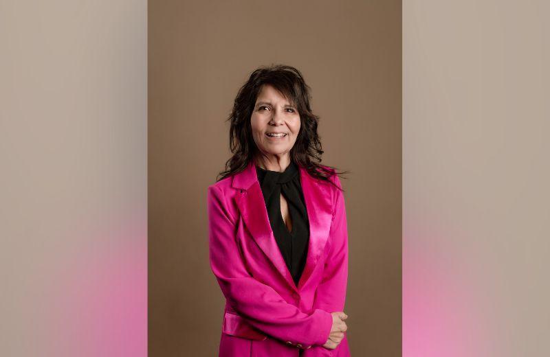 Patricia stands in a pink blazer and black top.