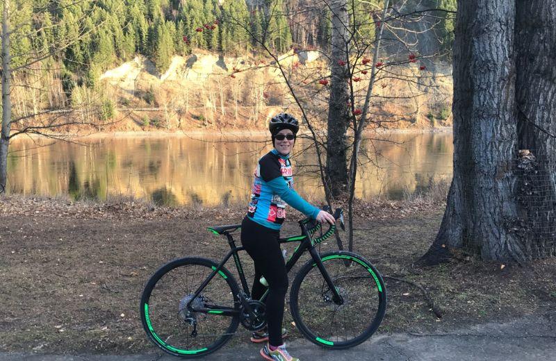 Gloria standing with her bike with the Fraser river in the background