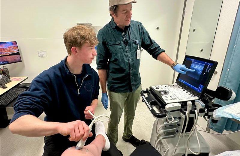 Dr. Tracy Morton and his son, Lief, scanning a patient’s knee bedside to prepare for an injection.