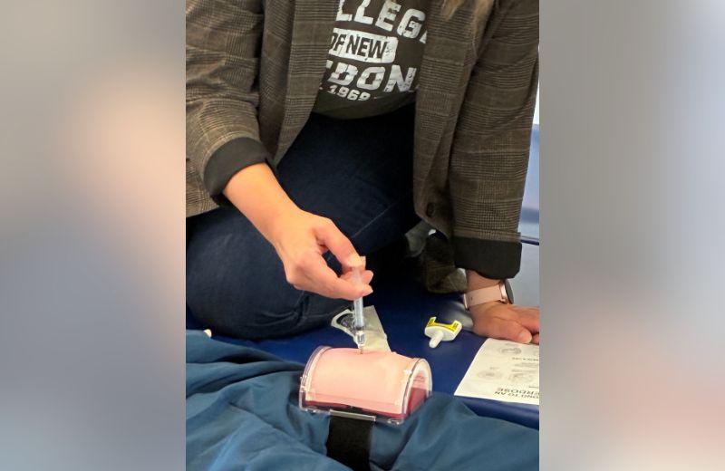 a student holding a syringe while working ona  prosthetic body part