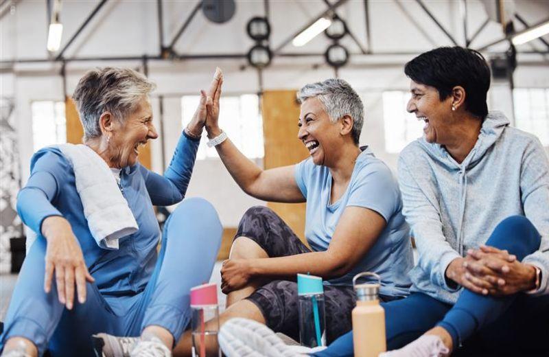 3 women sitting on the floor of an exercise gym laughing