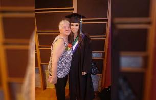 Adella stand with her granddaughter Addie who is wearing a graduation cap and gown