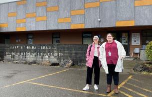 two woman stand outside in front of the health care centre