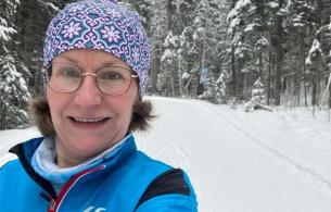 a woman with grey hair wearing a toque takes a selfie with a snowy background