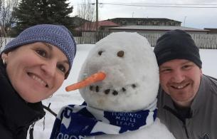 two people smile with snowman