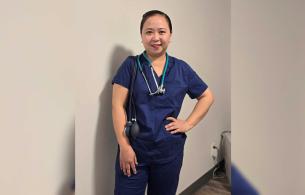Woman in scrubs stands with one hand on hip