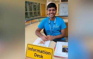 Aarya in a blue shirt sitting at the information desk ready to help