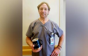 Male nurse stand in hallway holding an engraved cup