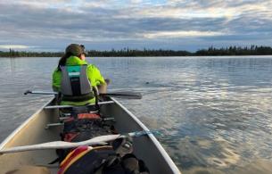 Maggie Kotowich sits at the front seat of a canoe over calm waters