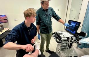 Dr. Tracy Morton and his son, Lief, scanning a patient’s knee bedside to prepare for an injection.