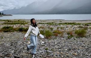 Tiffannie walking over white beach wood set against a lake and mountains in the background