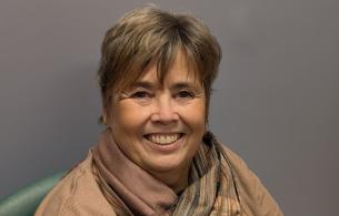 Woman with short hair wears a brown scarf around her neck