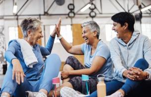 3 women sitting on the floor of an exercise gym laughing